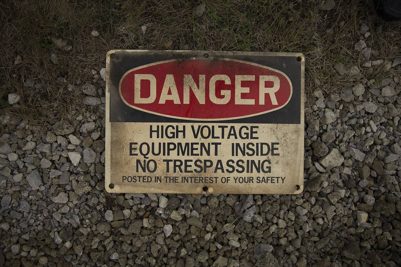 Danger High Voltage Equipment Inside sign lying on gravel