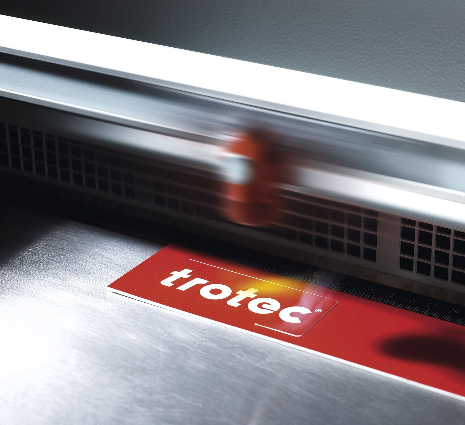 Laser engraver marking lettering into a red plate